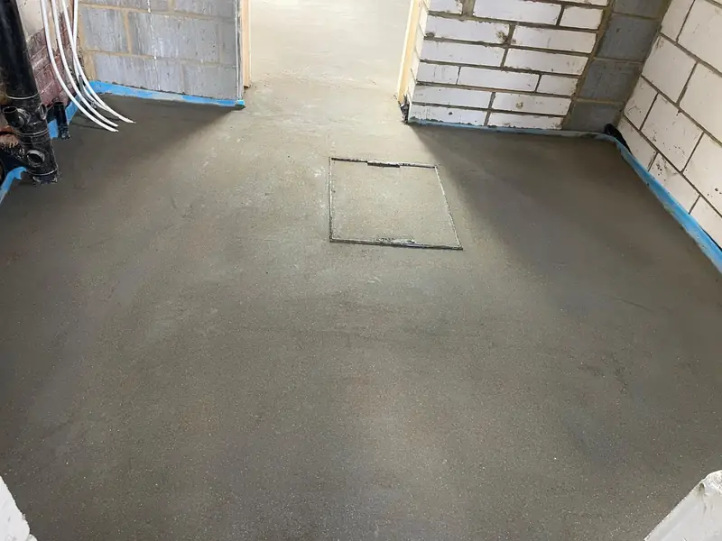 Completed extension floor screed with a floor access hatch left in position