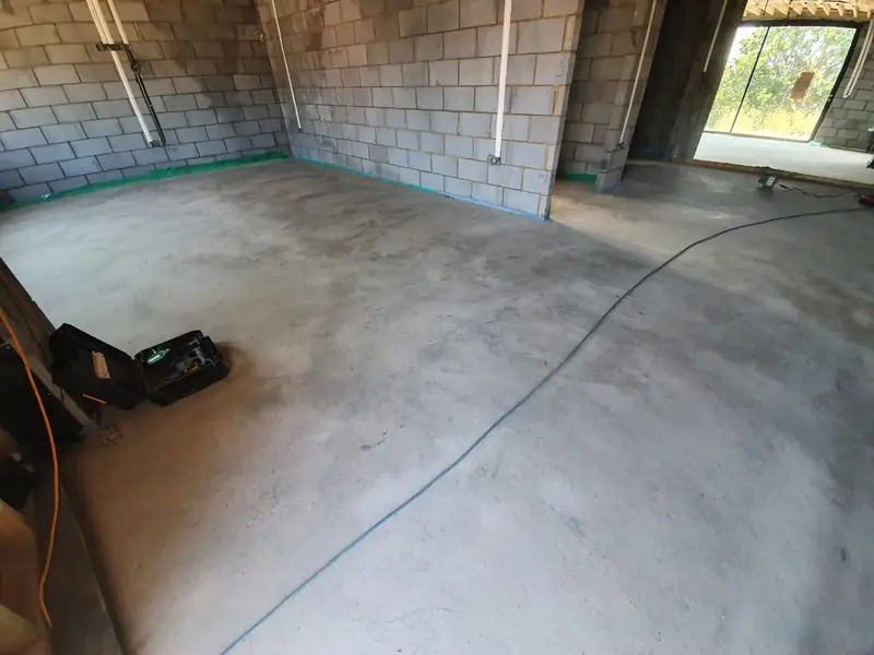 Floor screed laid wall to wall in a blockwork room with natural light from the windows