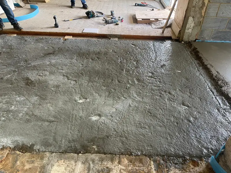Close view of freshly compacted screed with a trowelled surface at the room edge