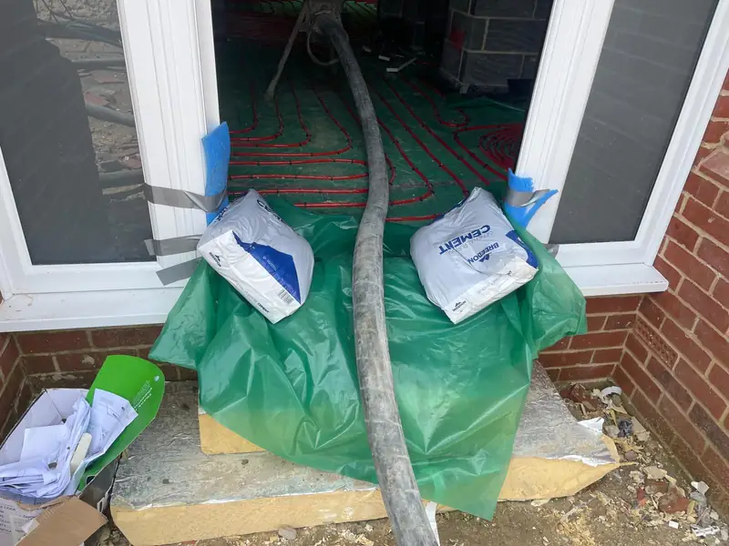 Screed hose fed through a doorway with materials protected on the threshold