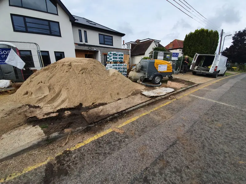 Screed sand delivered on a driveway alongside the screed pump outside a new house