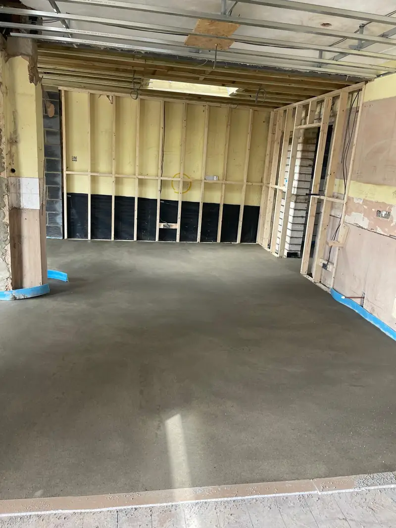 Timber-framed room with insulation boards on the walls and a new screed floor