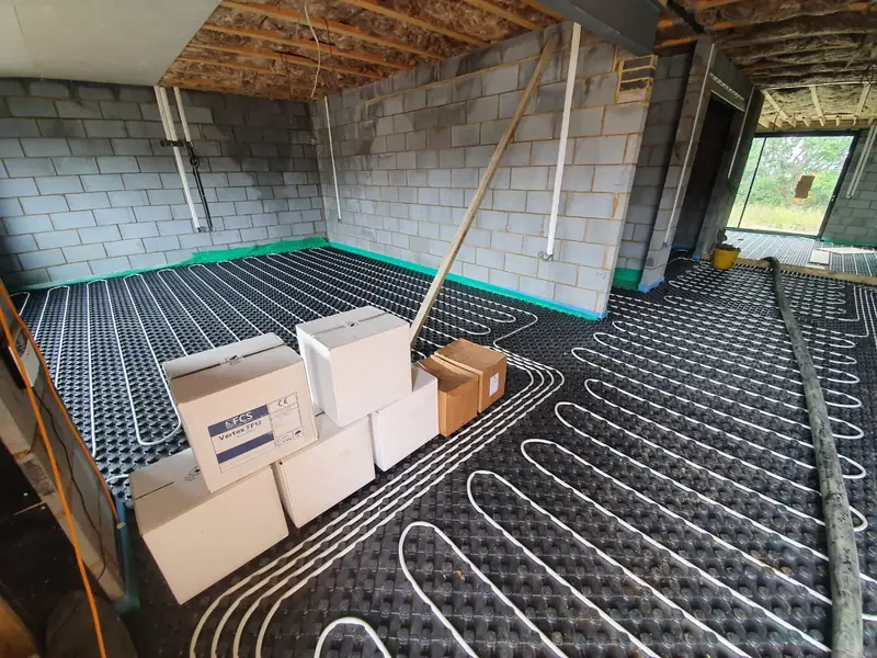 Underfloor heating pipes clipped to insulation panels with edge strip fitted, ready for screed